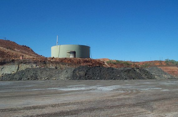 A large tank is sitting on top of a pile of dirt.