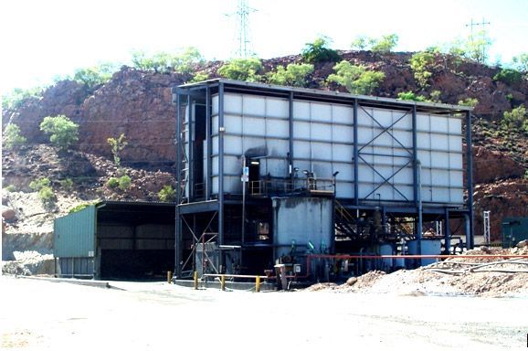 A large building is sitting on top of a hill surrounded by trees