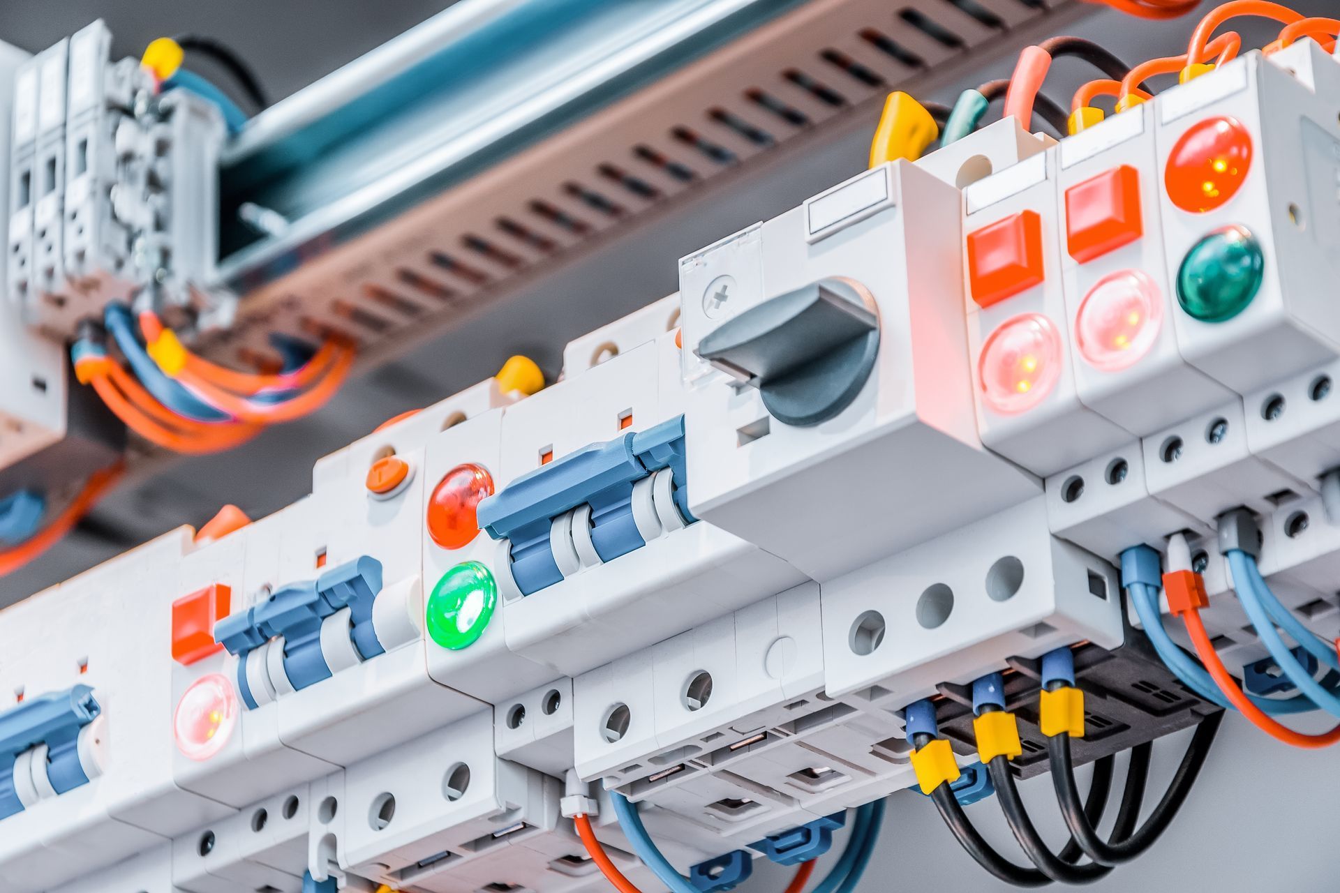 Pannello di controllo elettrico con interruttori, spie luminose e cablaggio in un ambiente di fabbrica.