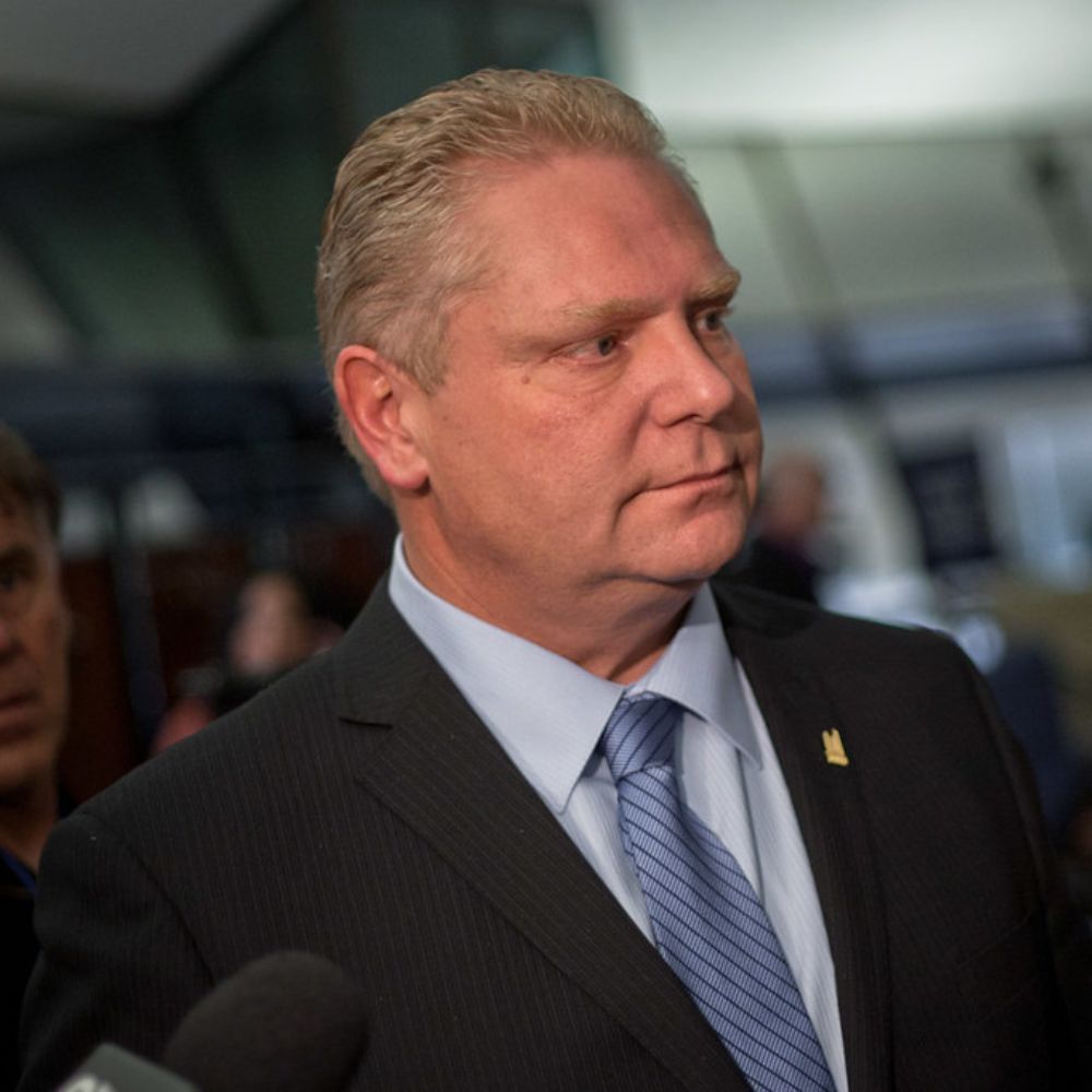 Doug Ford in a suit and tie is talking into a microphone