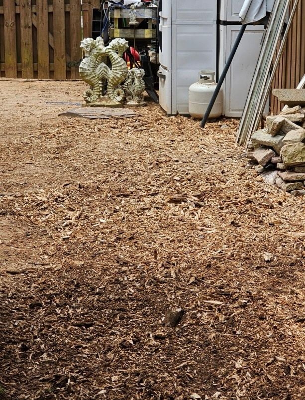 A pile of wood chips is sitting on the ground in a backyard.