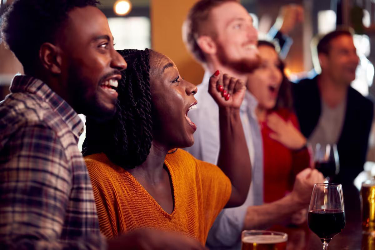 A group of people are sitting at a bar watching a game.