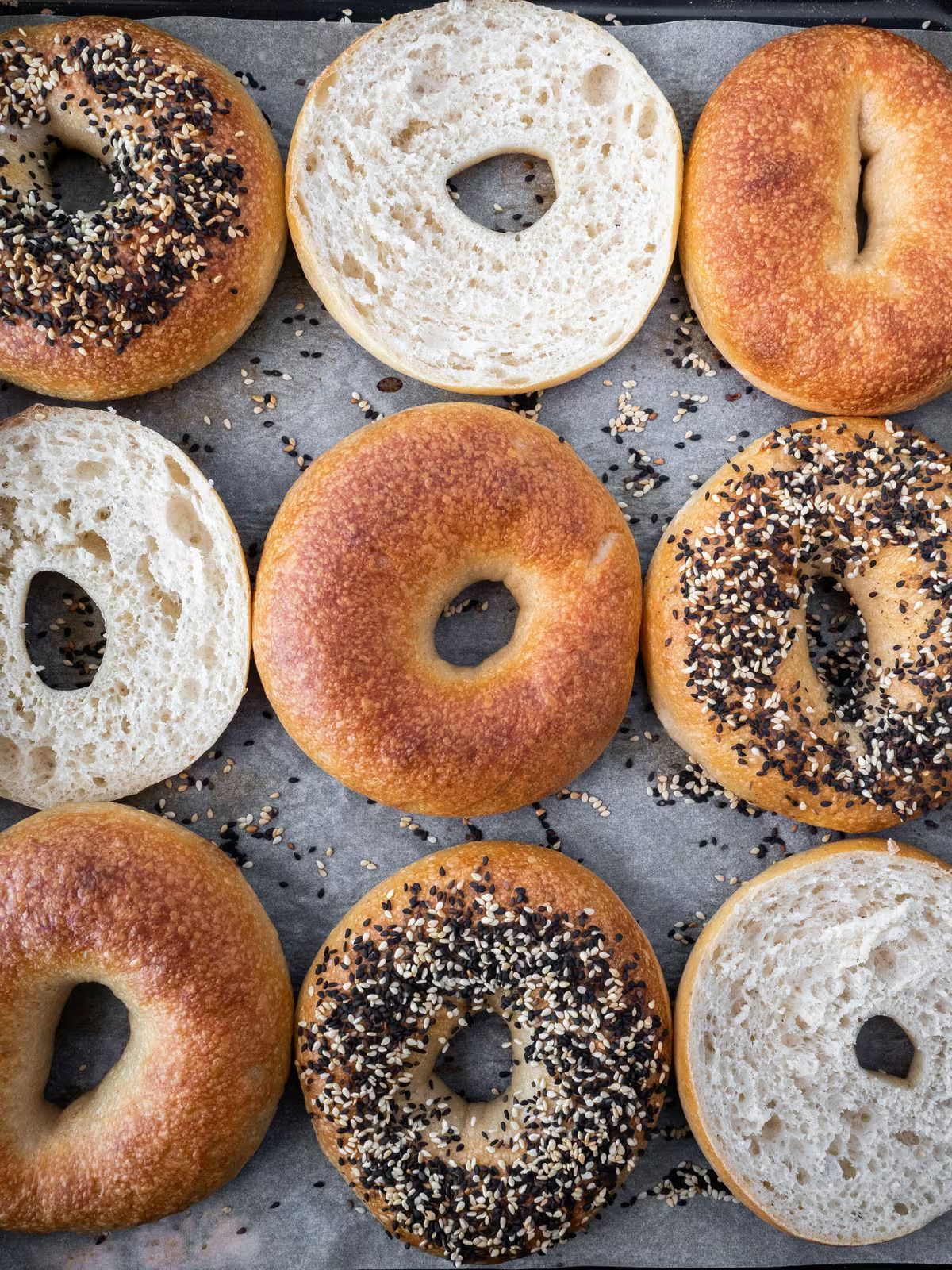 A bunch of bagels are sitting on a tray on a table.