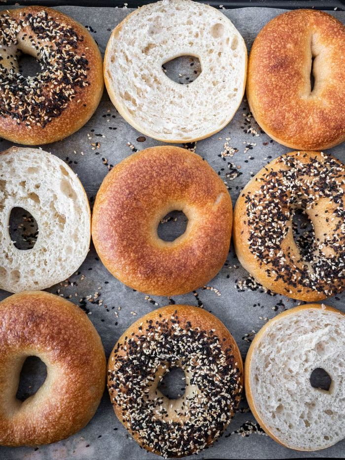 A bunch of bagels are sitting on a tray on a table.