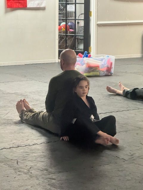 A man and a little girl are sitting on the floor