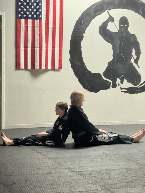 Two kids are doing a split in front of an american flag