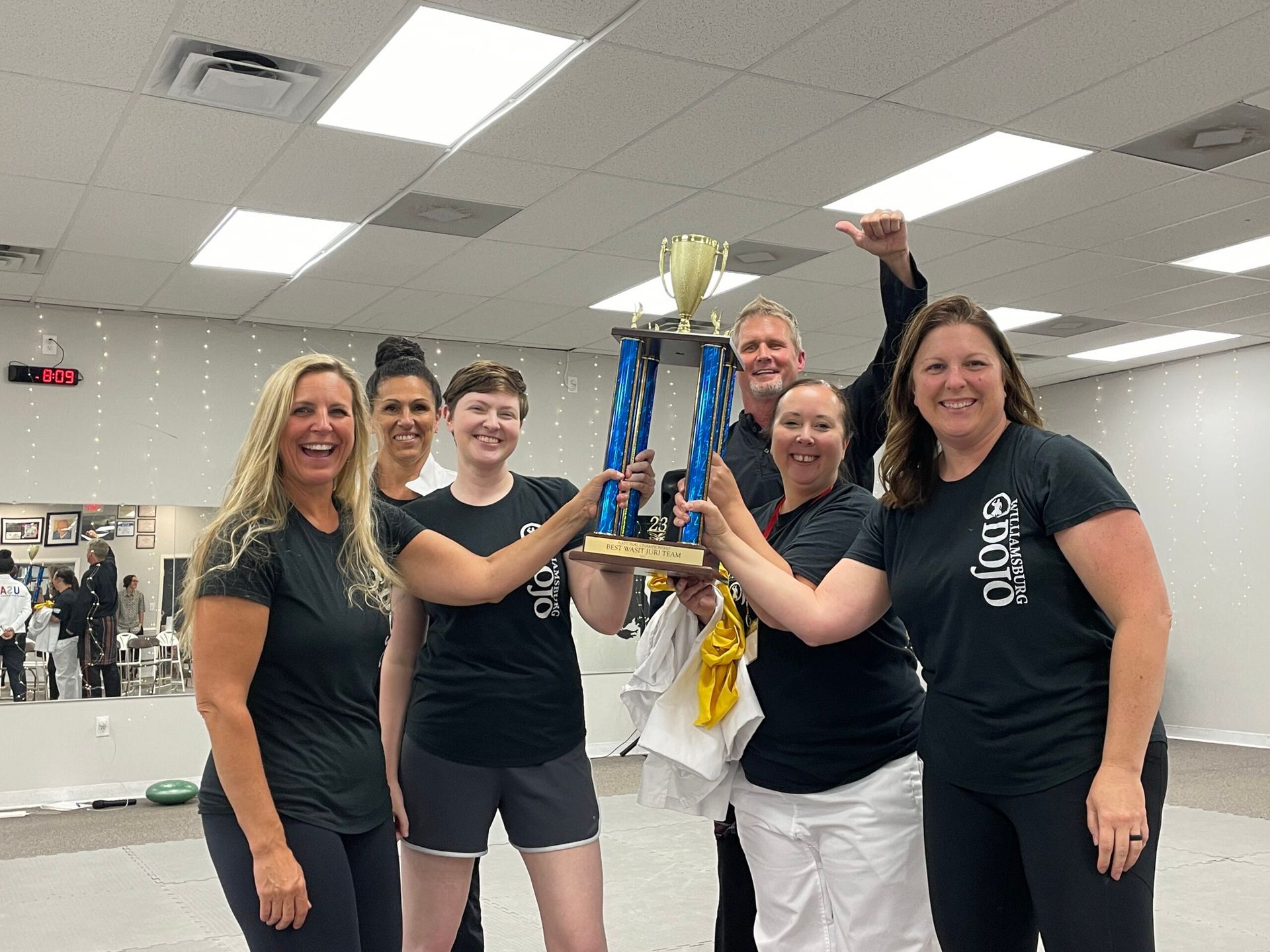 A group of women are holding a trophy in a gym.