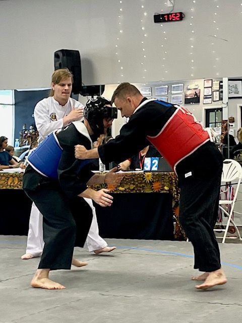 Two men are fighting in a gym with a digital clock on the wall above them