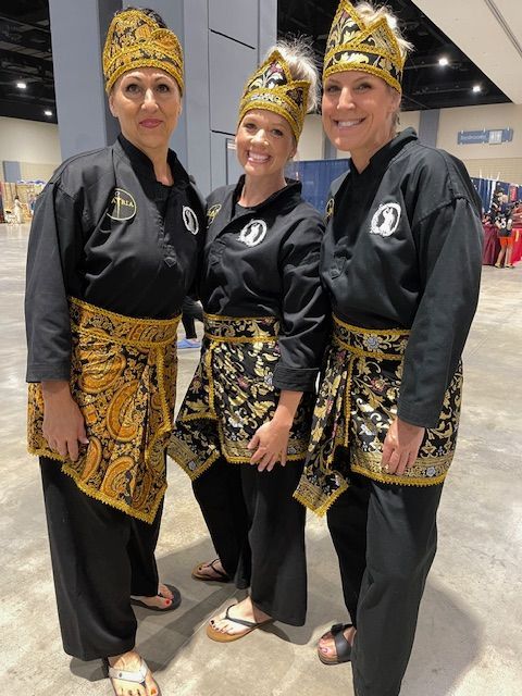 Three women are posing for a picture wearing black and gold outfits