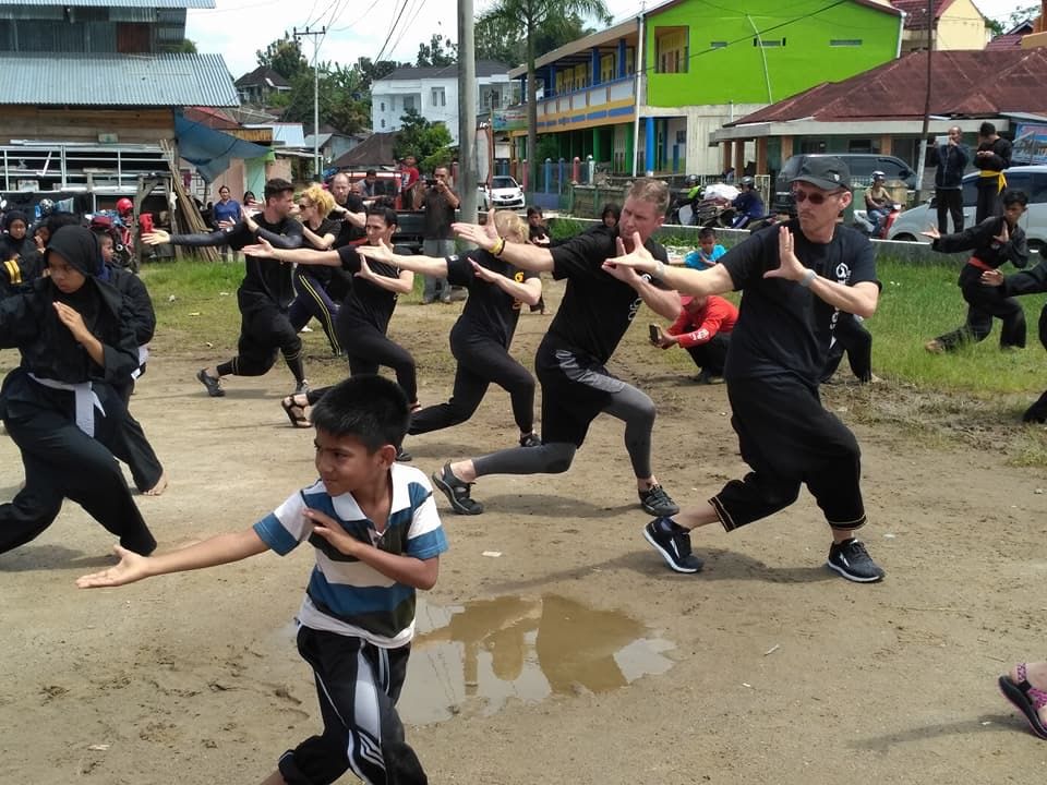 A group of people are practicing martial arts in a dirt field