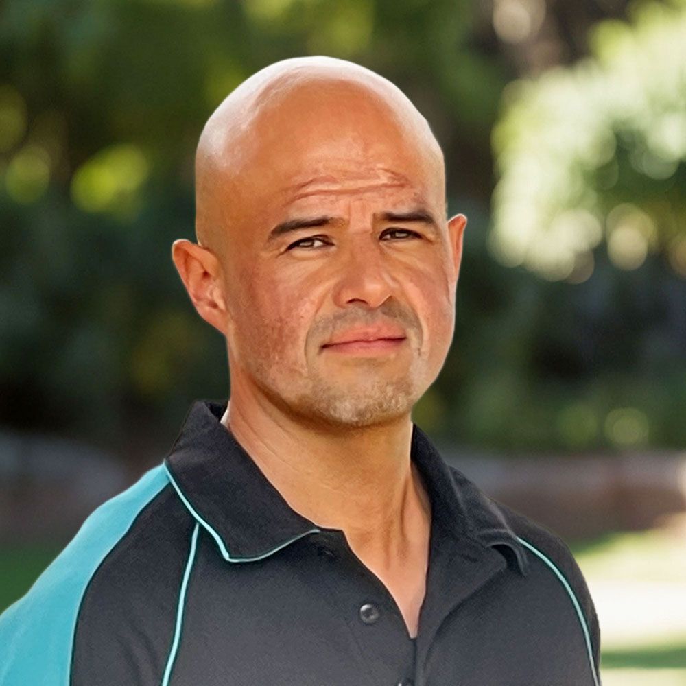 A man wearing a black and blue shirt looks at the camera