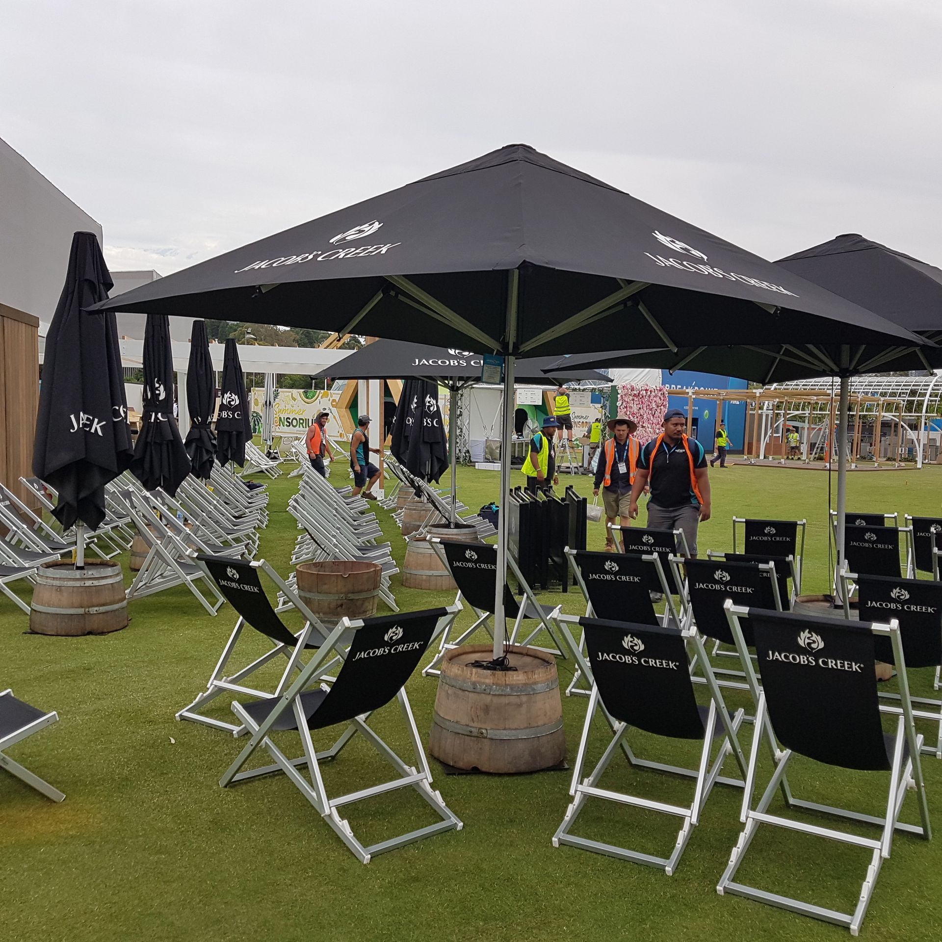 A row of black folding chairs under black umbrellas