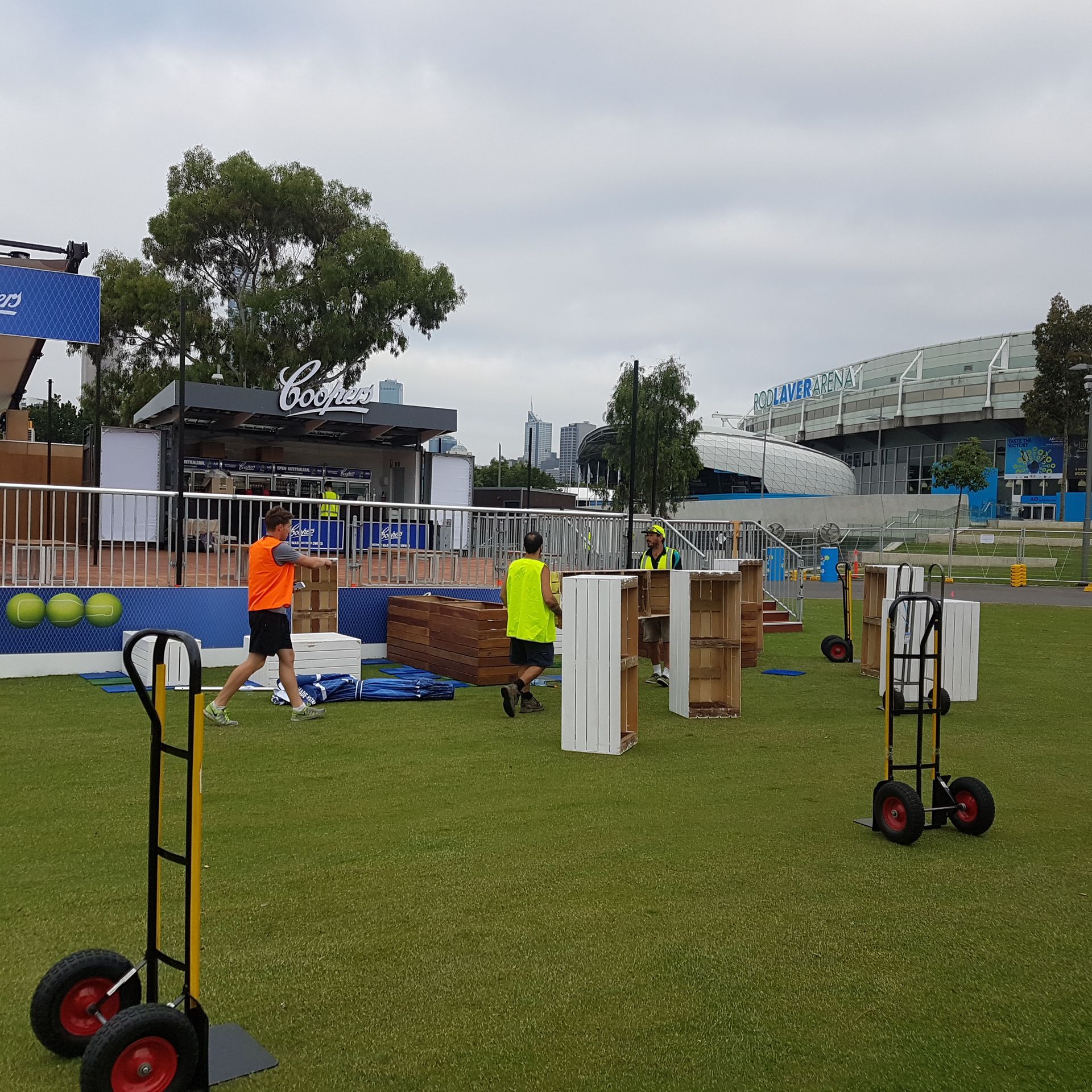 A man in an orange shirt is pushing a cart in a field