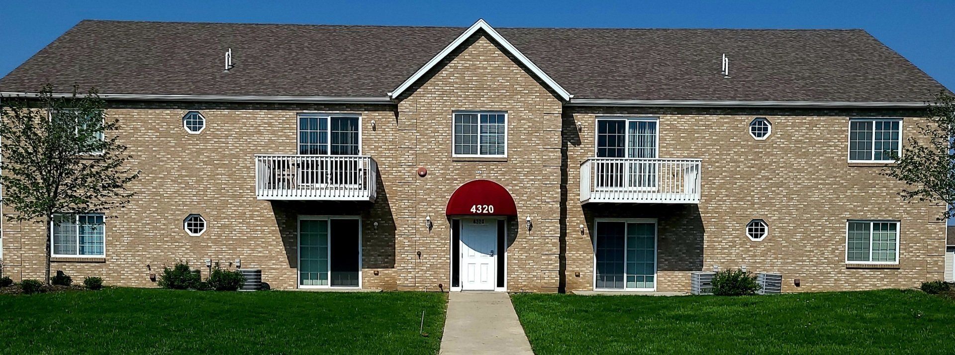 A brick apartment building with a red awning on the door