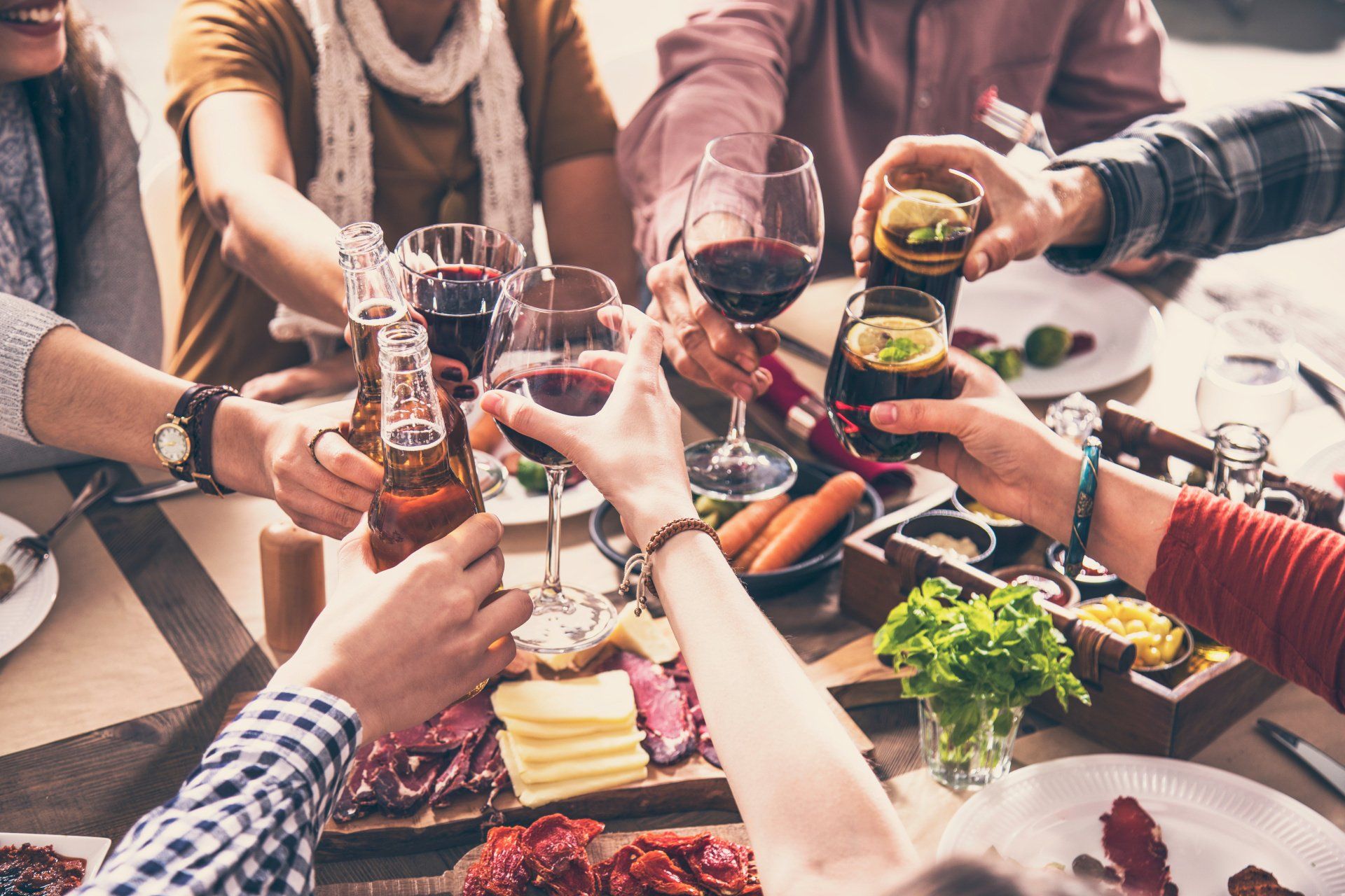 A group of people are sitting around a table toasting with wine glasses.