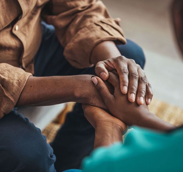 A person is holding another person 's hand while sitting on a couch.