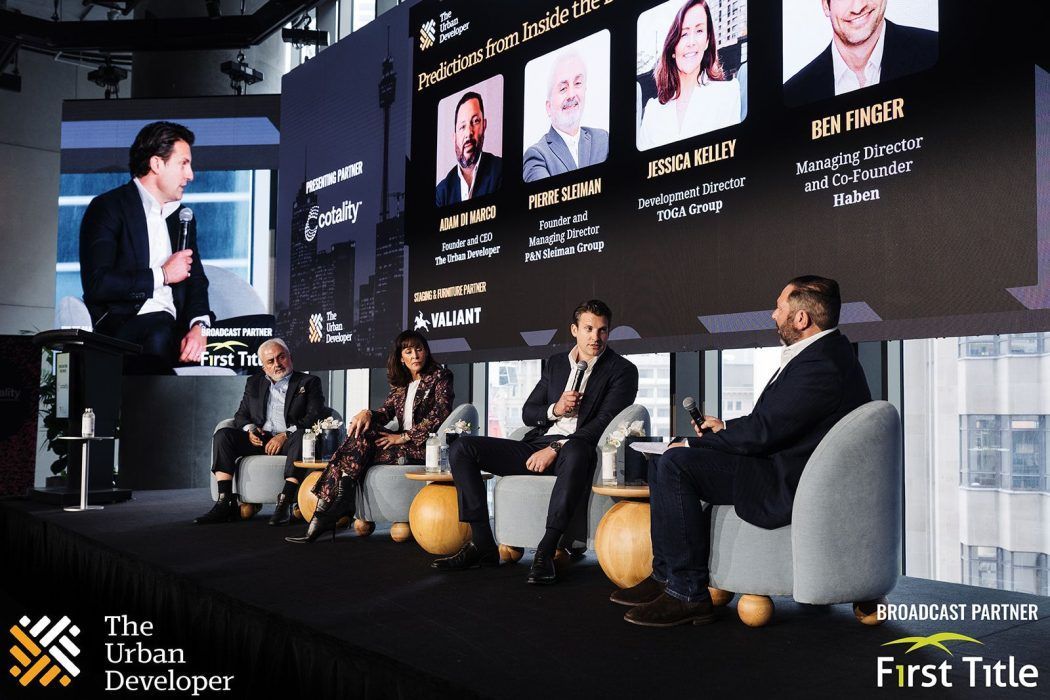A panel discussion at The Urban Developer event, featuring four speakers seated on stage in front of a digital screen.