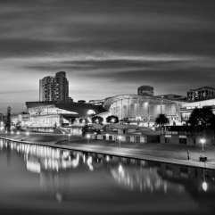 Black and white view of the Adelaide Convention Centre and city skyline reflecting on the River Torrens at twilight.