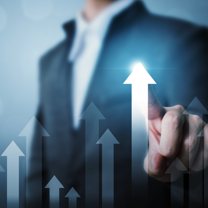 A person in a business suit touches a glowing, upward-pointing arrow on a digital display of rising growth arrows.