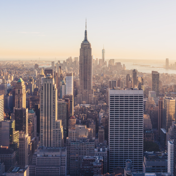 Aerial view of the New York City skyline at sunset, featuring the Empire State Building towering over skyscrapers.