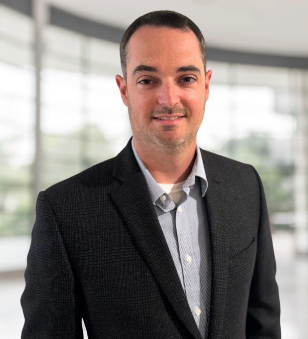 Man in blazer with light blue shirt and dark hair