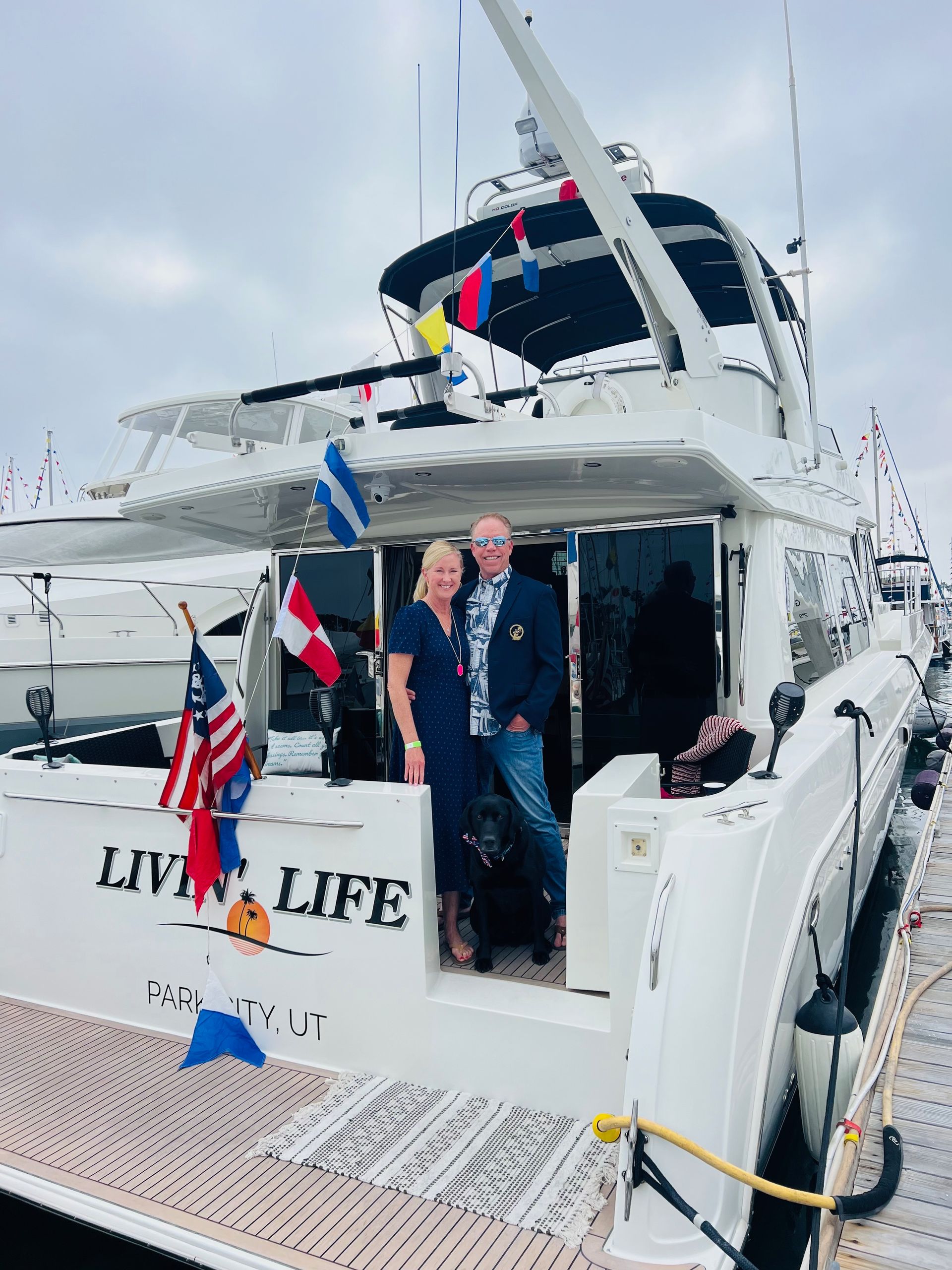 A man and woman are standing on the deck of a boat called live life