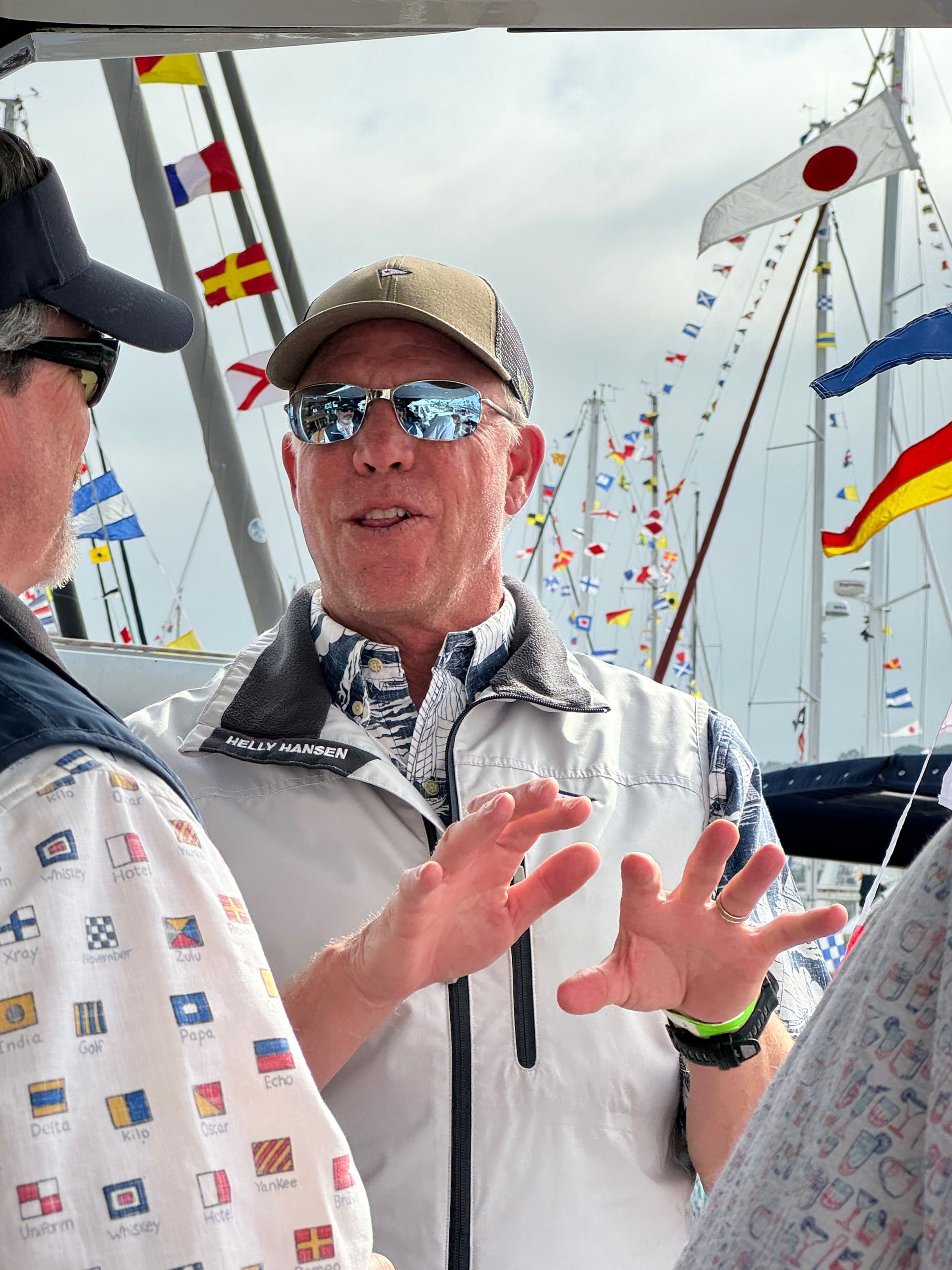 A man wearing sunglasses is talking to another man on a boat