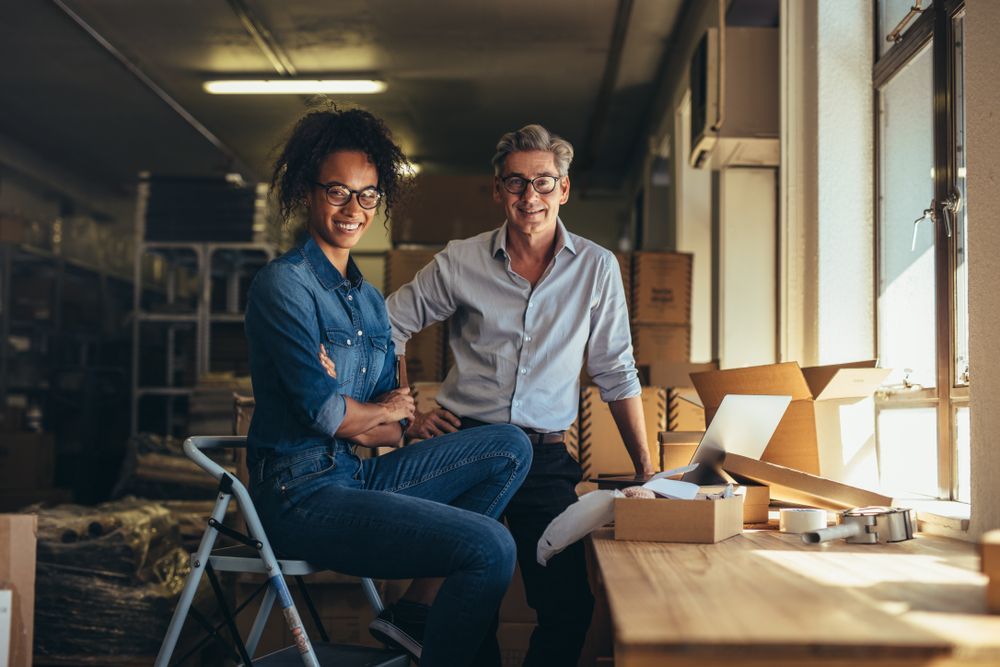 A man and a woman are sitting next to each other in a warehouse.