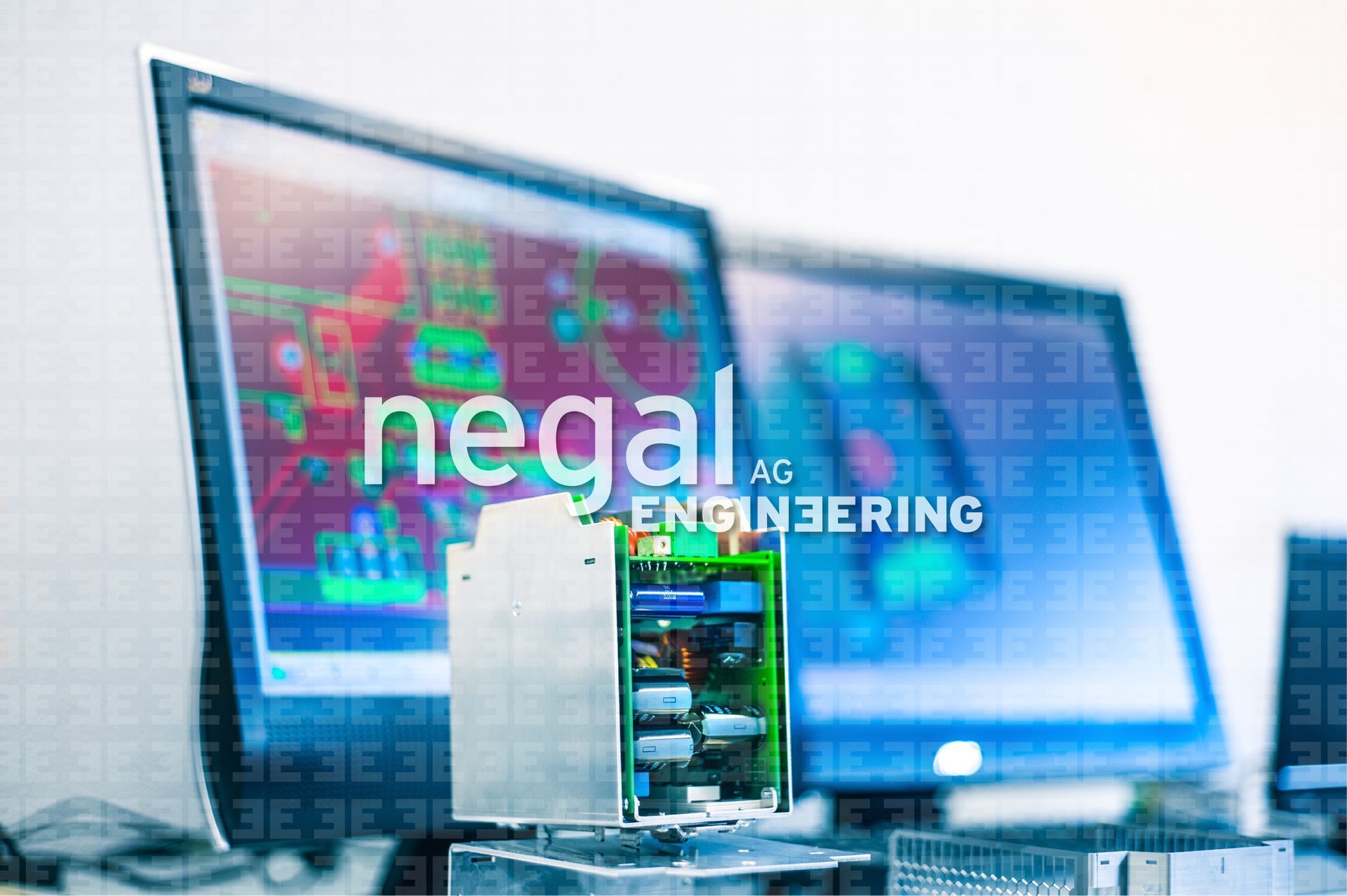 In einem hell erleuchteten Büro steht eine Leiterplatte vor zwei Computermonitoren, auf denen Schaltpläne und 3D-Renderings angezeigt werden.