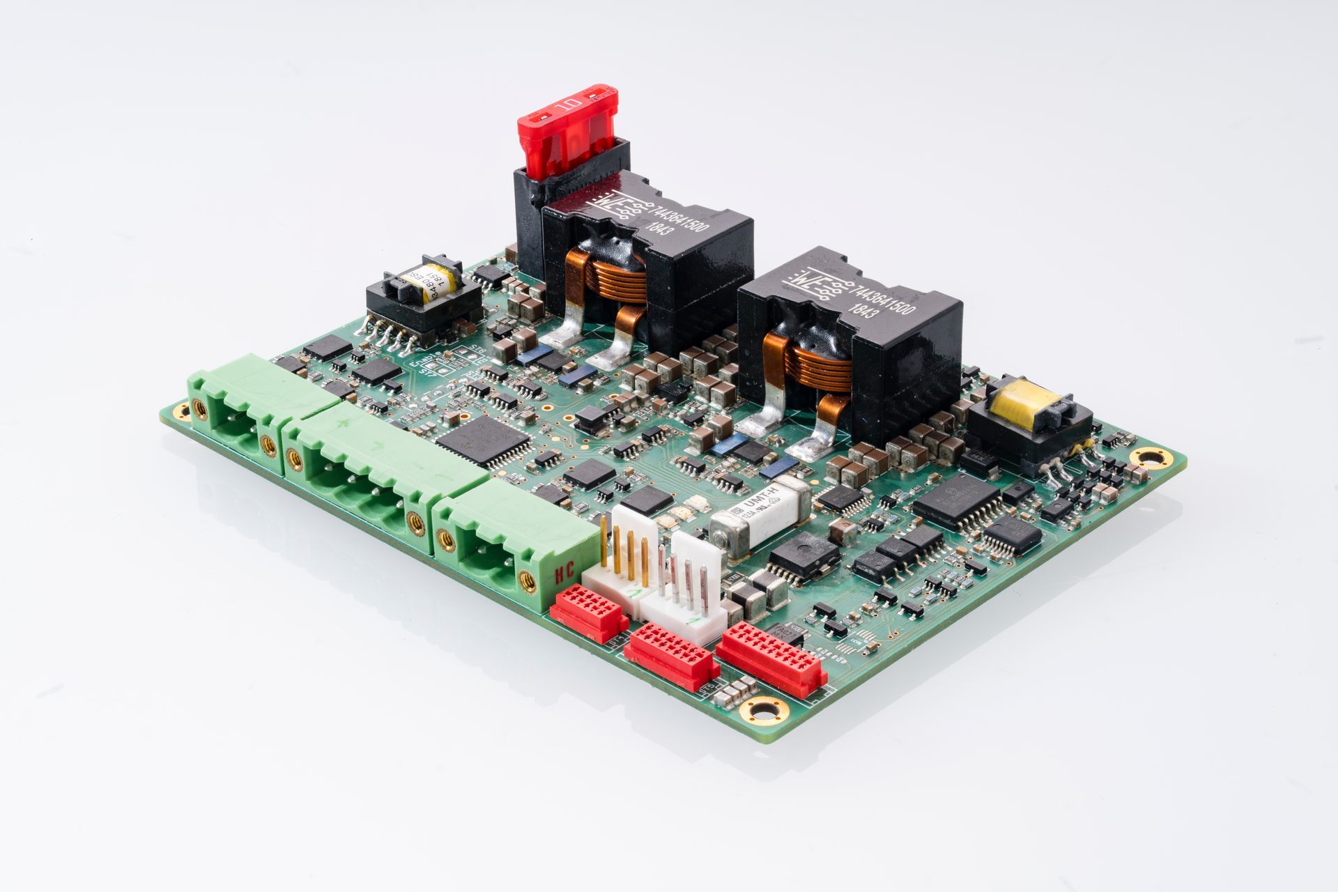 Printed circuit board with green connectors, black transformers and various electronic components.