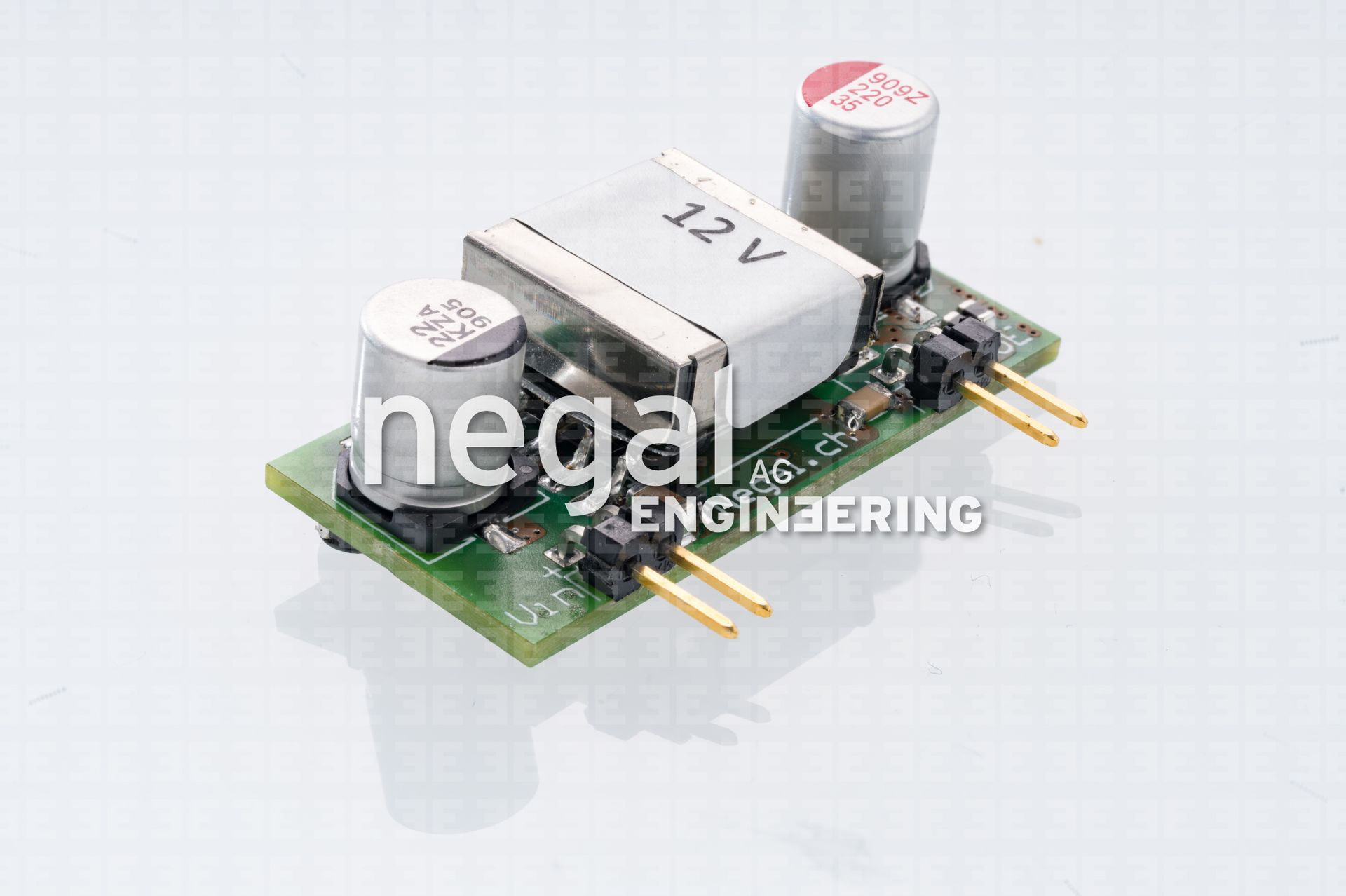 Grüne Platine mit einem 12V-Stromrichtermodul und zwei Zylinderkondensatoren.