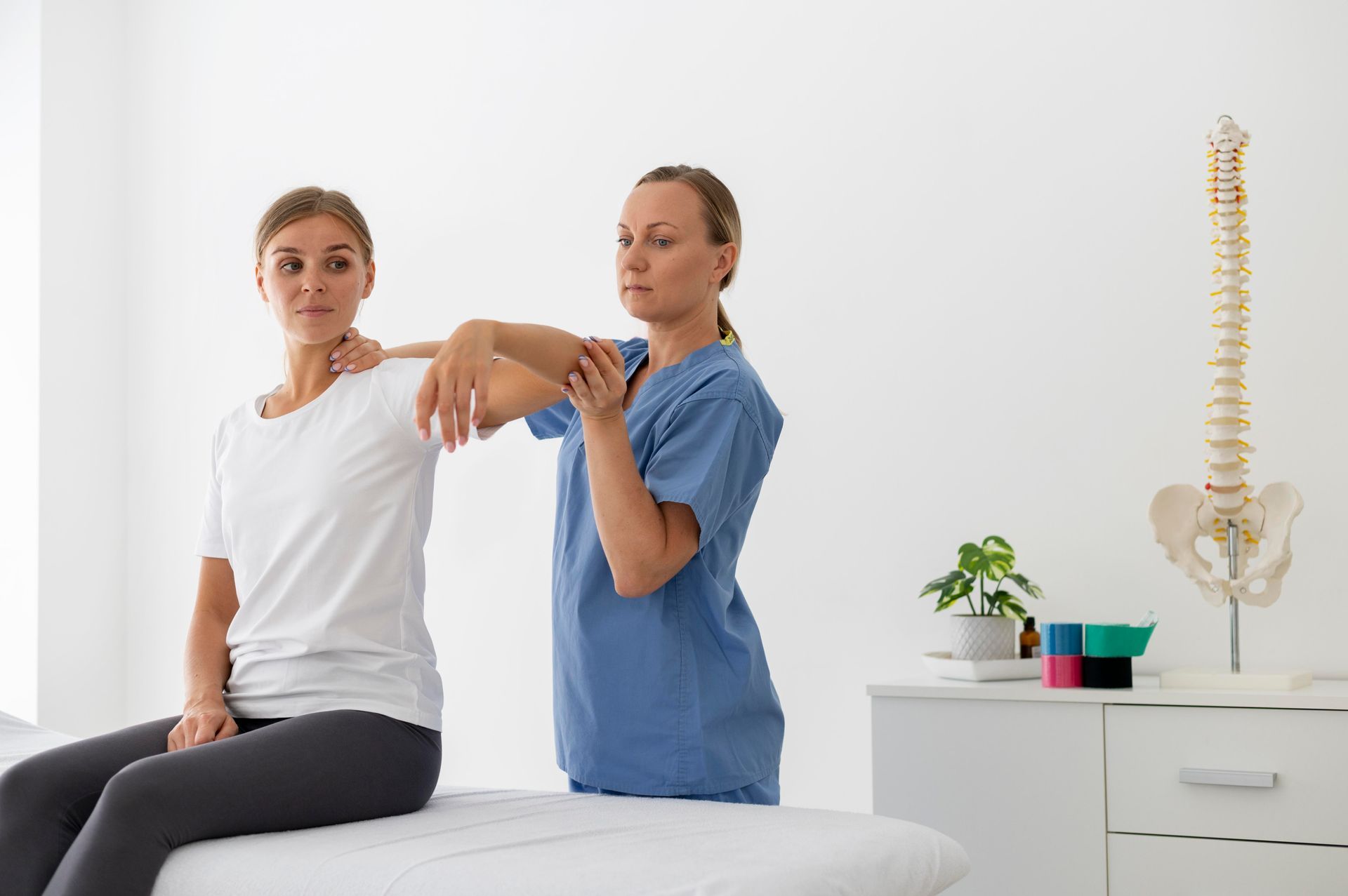 A woman is sitting on a table while a doctor examines her back.