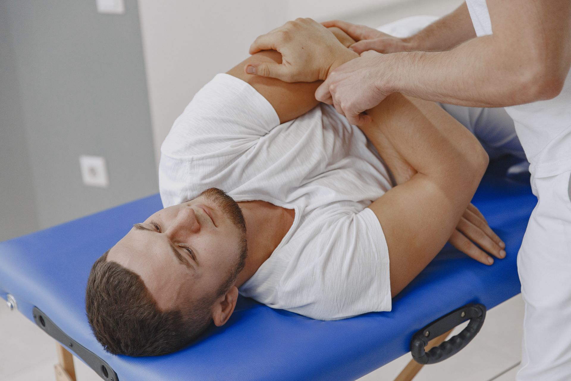 A man is laying on a blue table getting a massage.