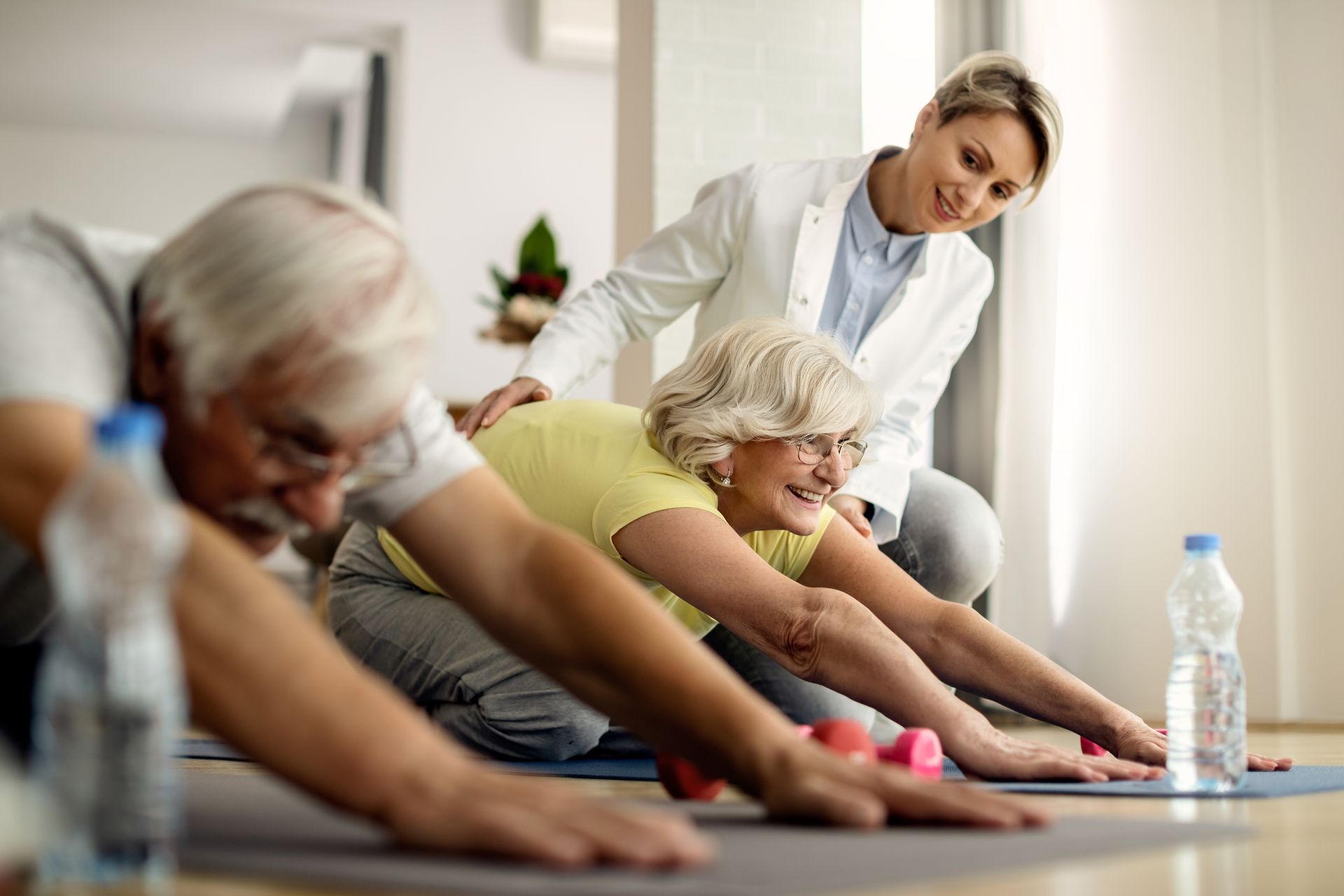 a group of elderly people are doing stretching exercises on a yoga mat .