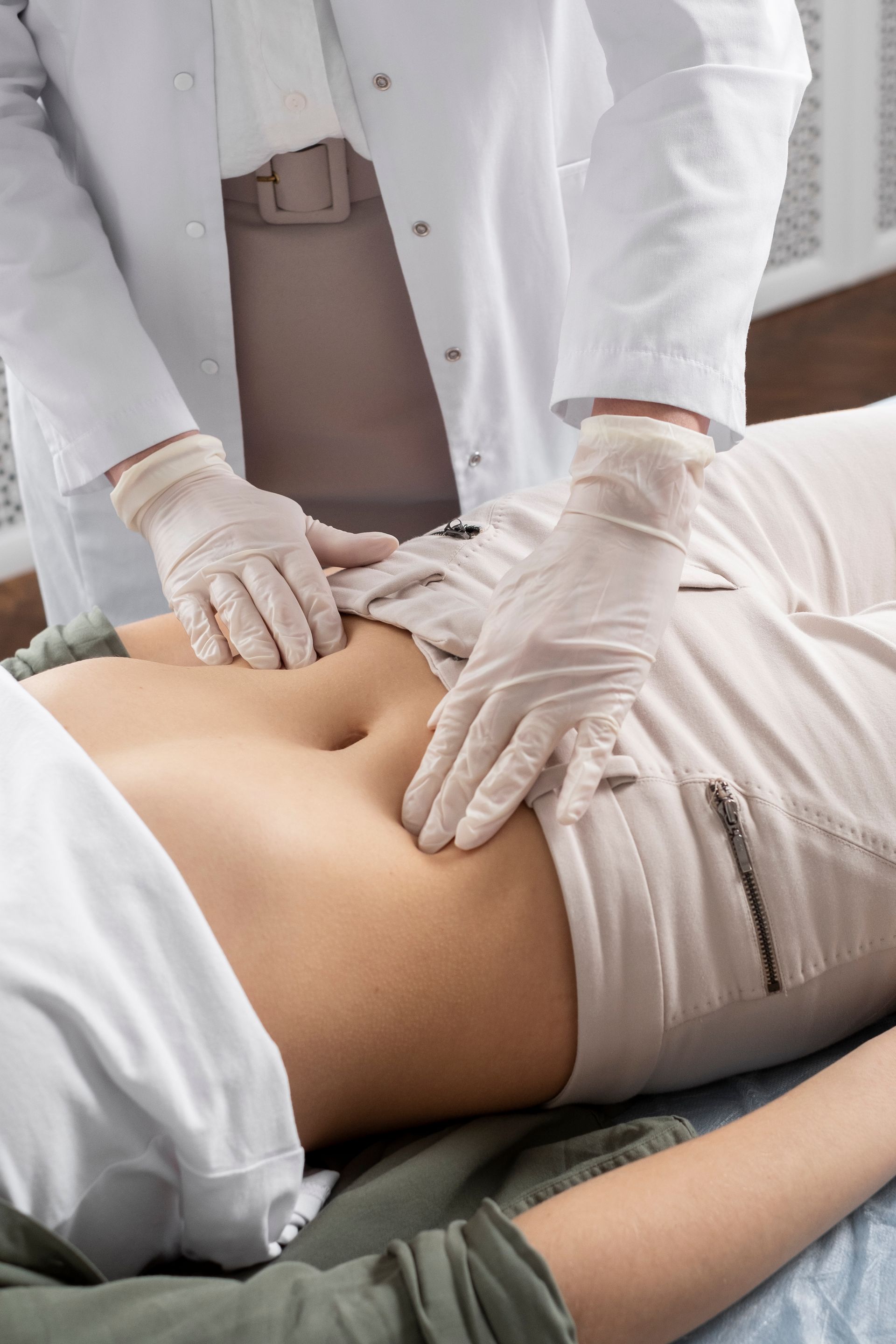 A woman is laying on a bed while a doctor examines her stomach.
