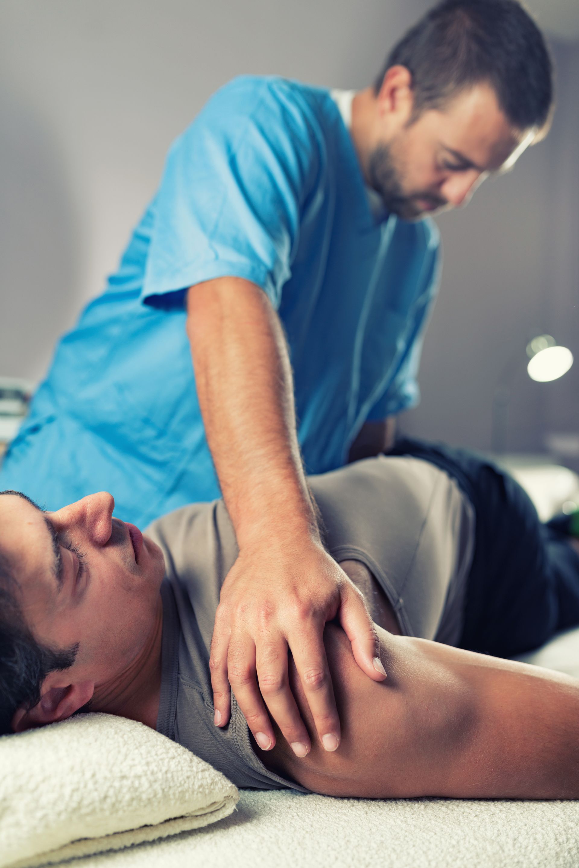 A man is laying on a bed getting a massage from a doctor.