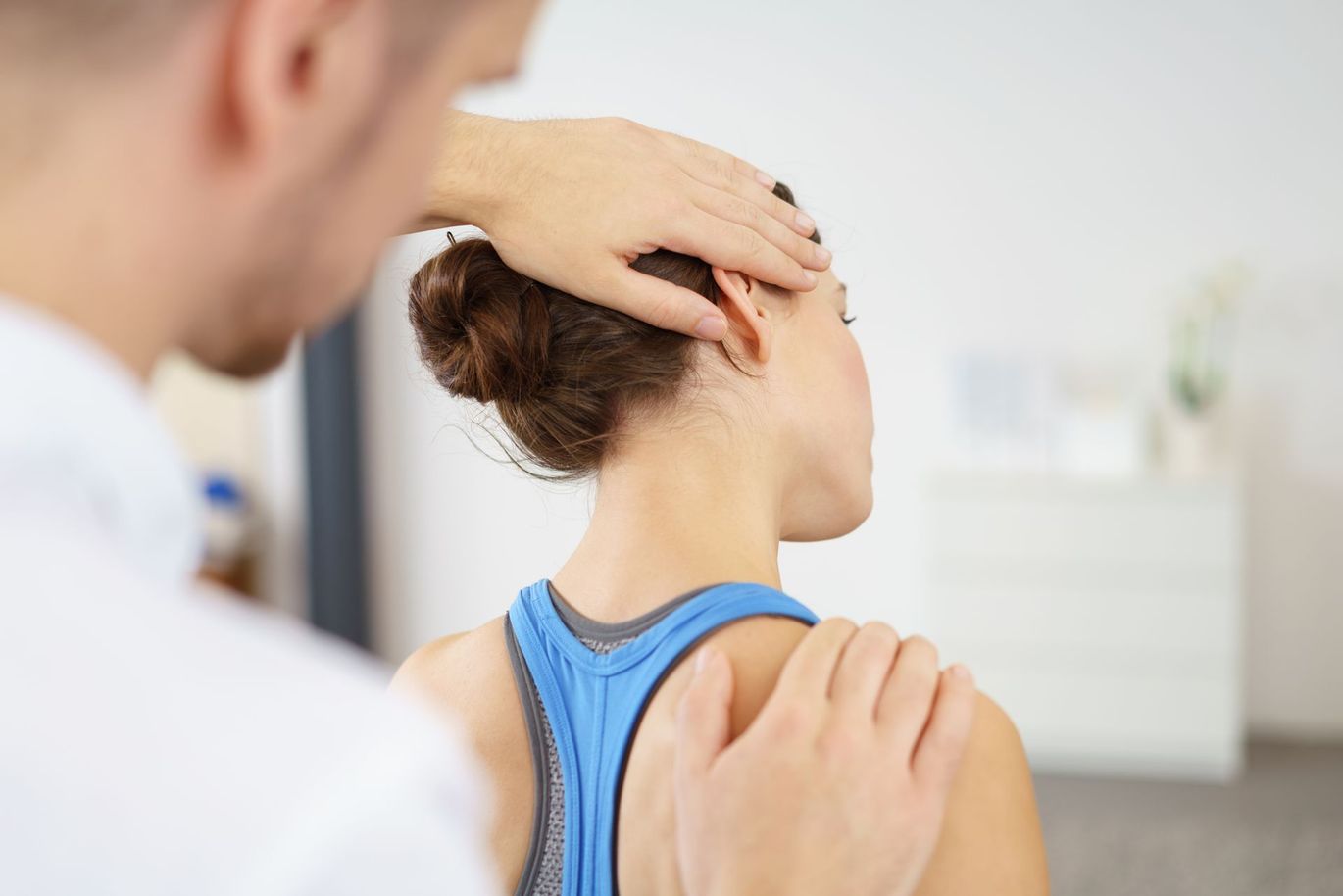 A man is examining a woman 's neck and shoulder.