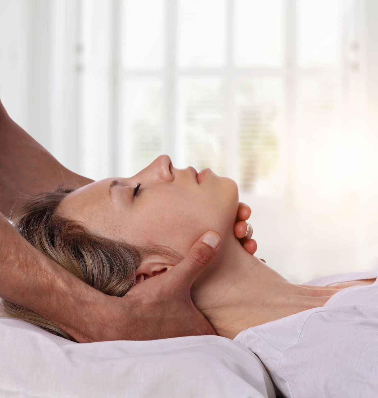 A woman is laying on a bed getting a massage from a man.