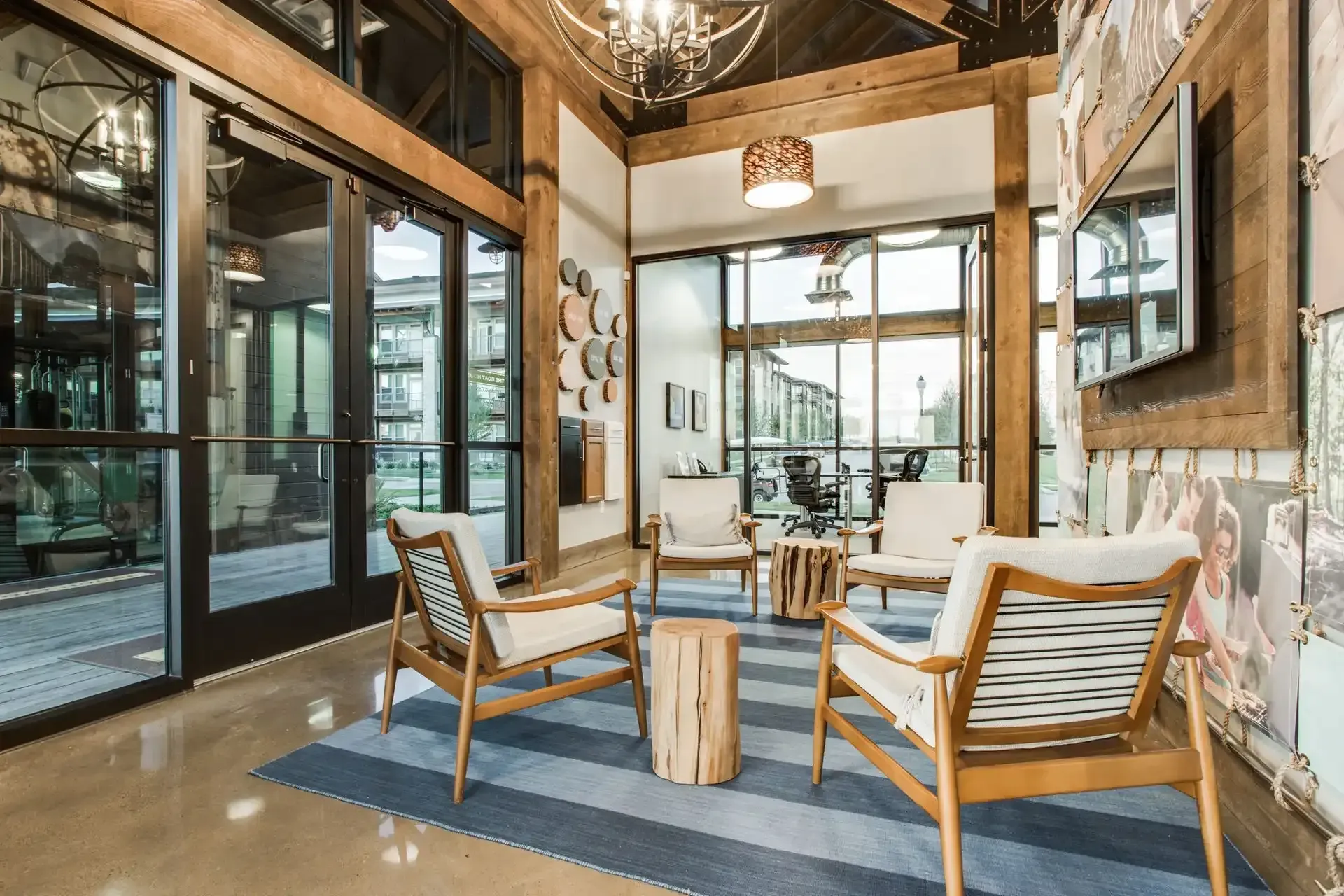 Lounge area with wood beams, glass doors, armchairs, and a striped rug at The Boat House, offers pet-friendly apartments and townhomes in The Colony, TX.