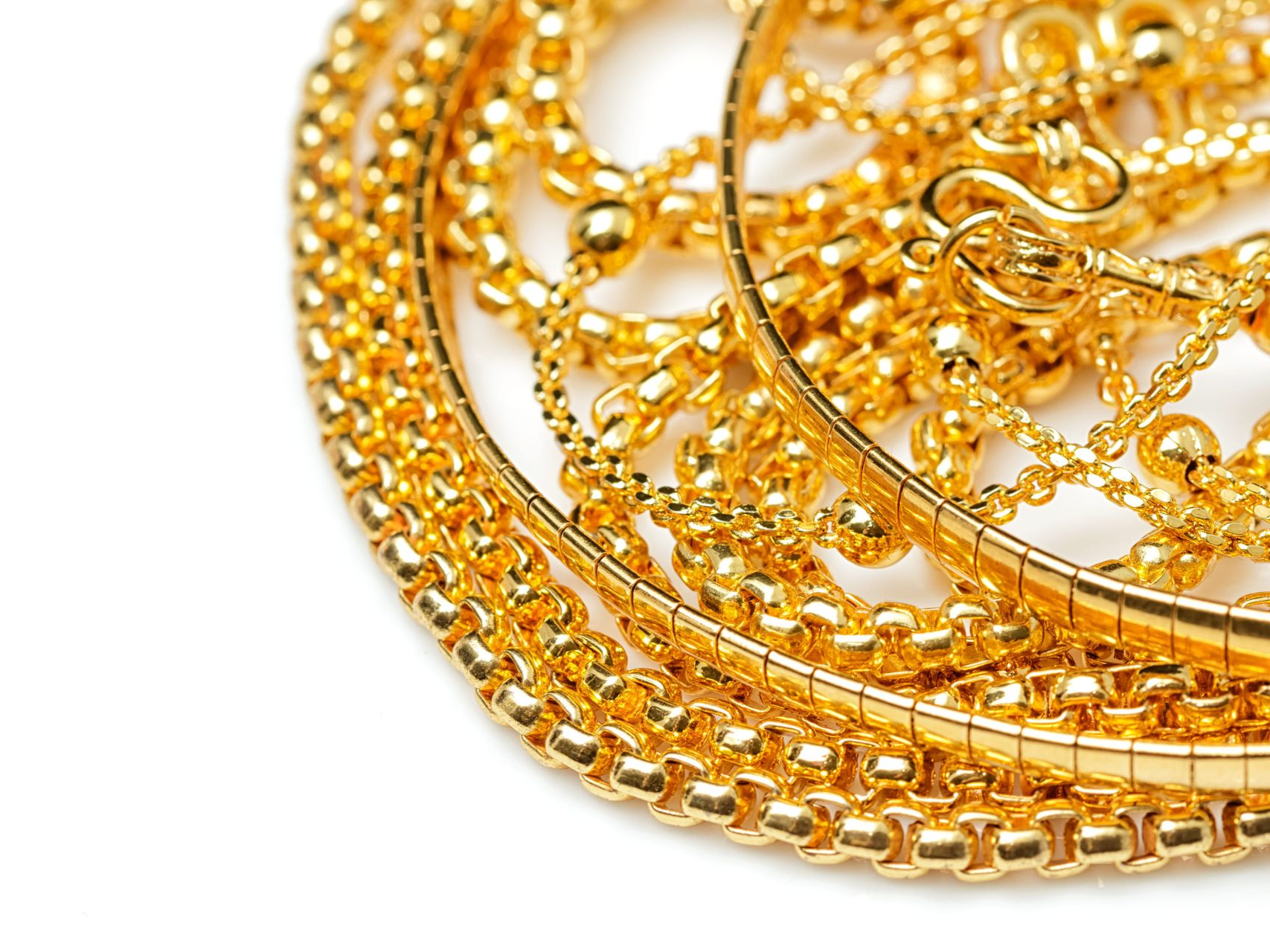 A close-up view of several layered gold necklaces with intricate chain designs and small, spherical beads.
