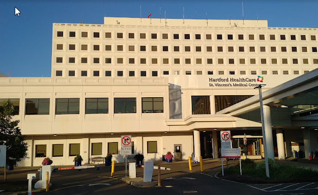 A large white building with a lot of windows and a parking lot in front of it.