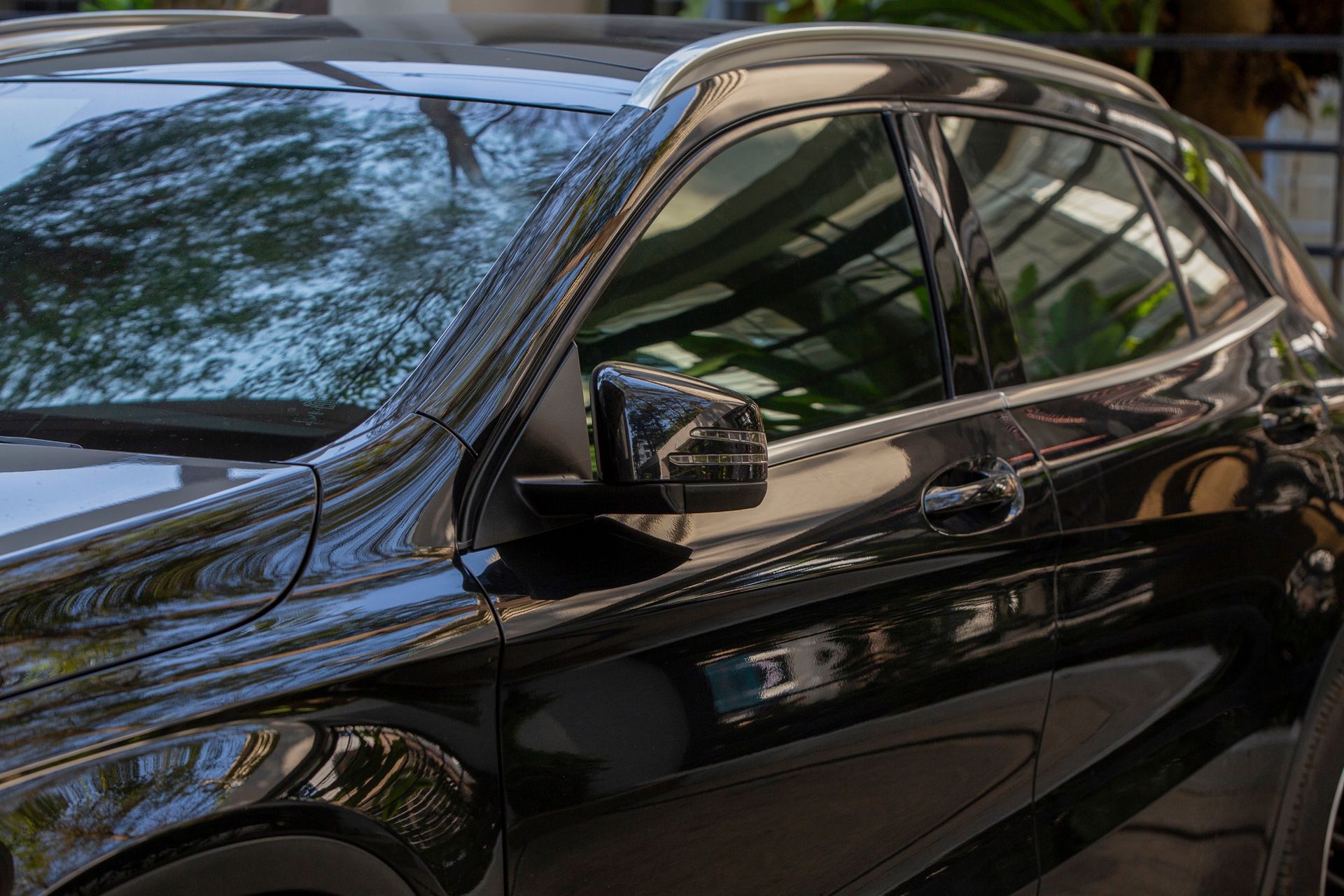 A close up of a black car parked in a parking lot.