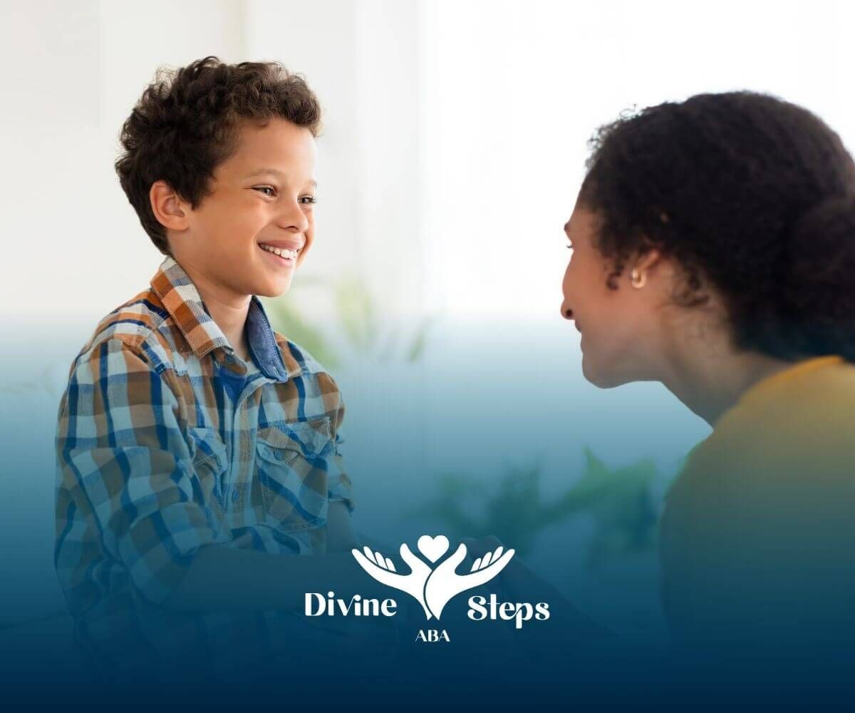 An ABA therapist and a boy are holding hands and smiling at each other in ABA therapy.
