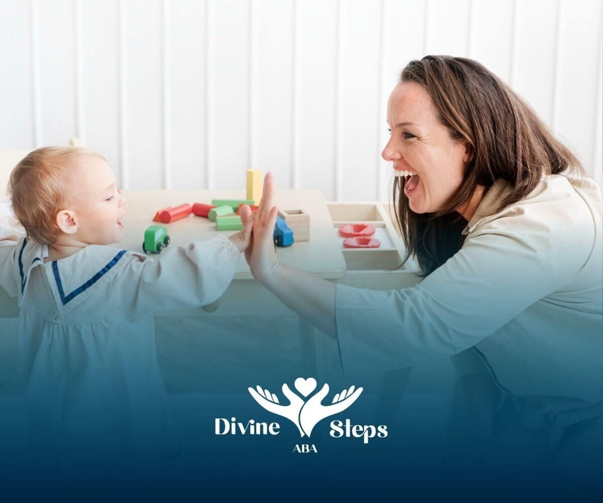 A BCBA is giving an autistic toddler a high five while playing with toys in ABA therapy.