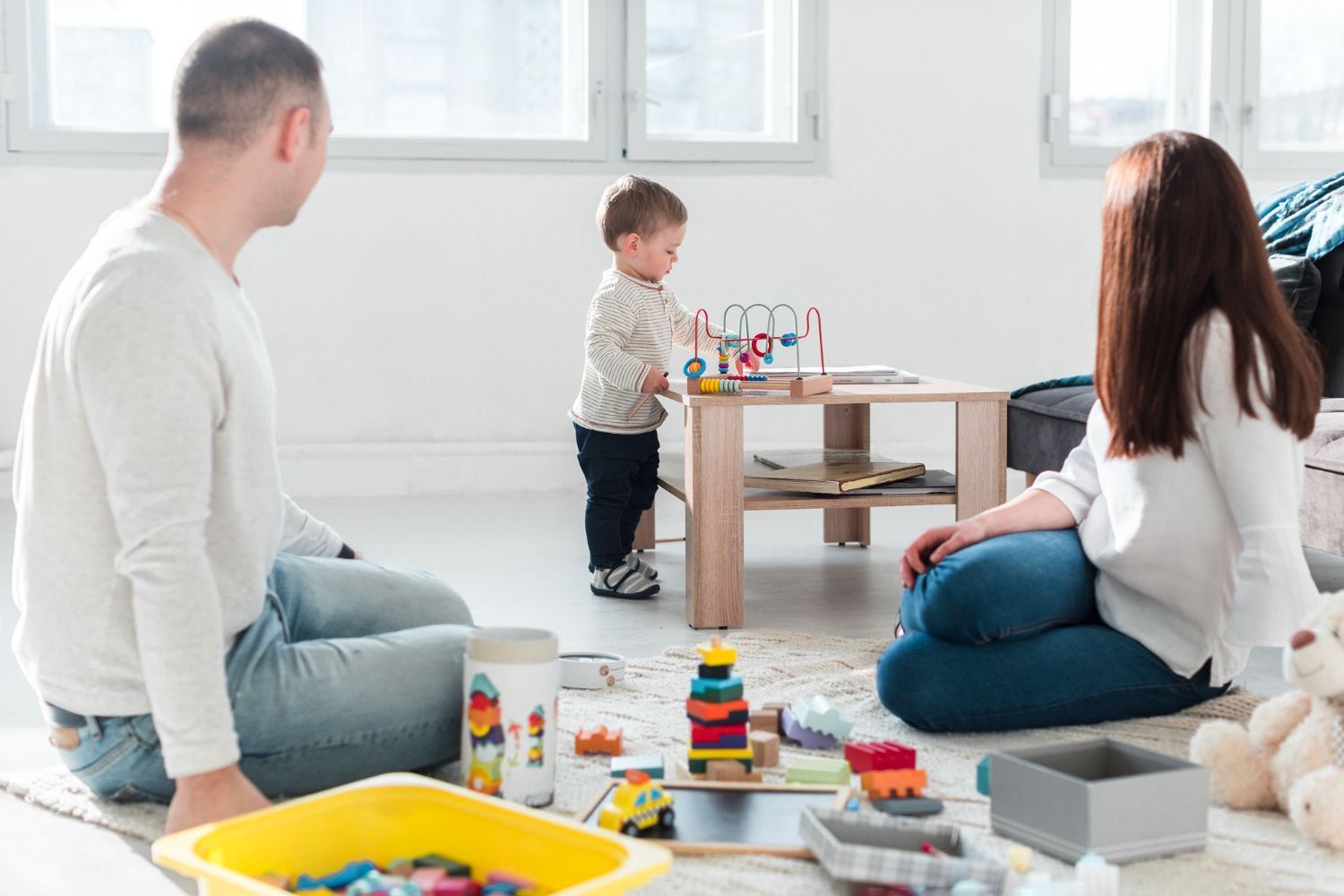 A family is sitting on the floor playing with toys.