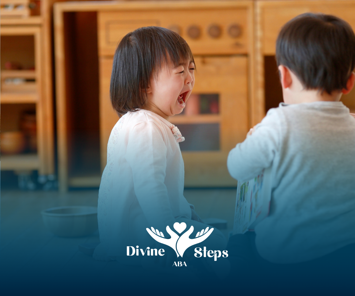 A young child cries, facing another in a light-wood playroom. The Divine Steps USA logo is at the bottom.