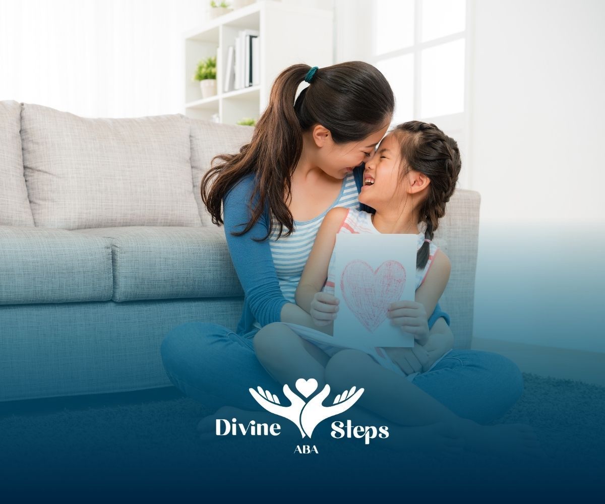 Mother and daughter embracing, smiling, seated on floor, holding a heart card.
