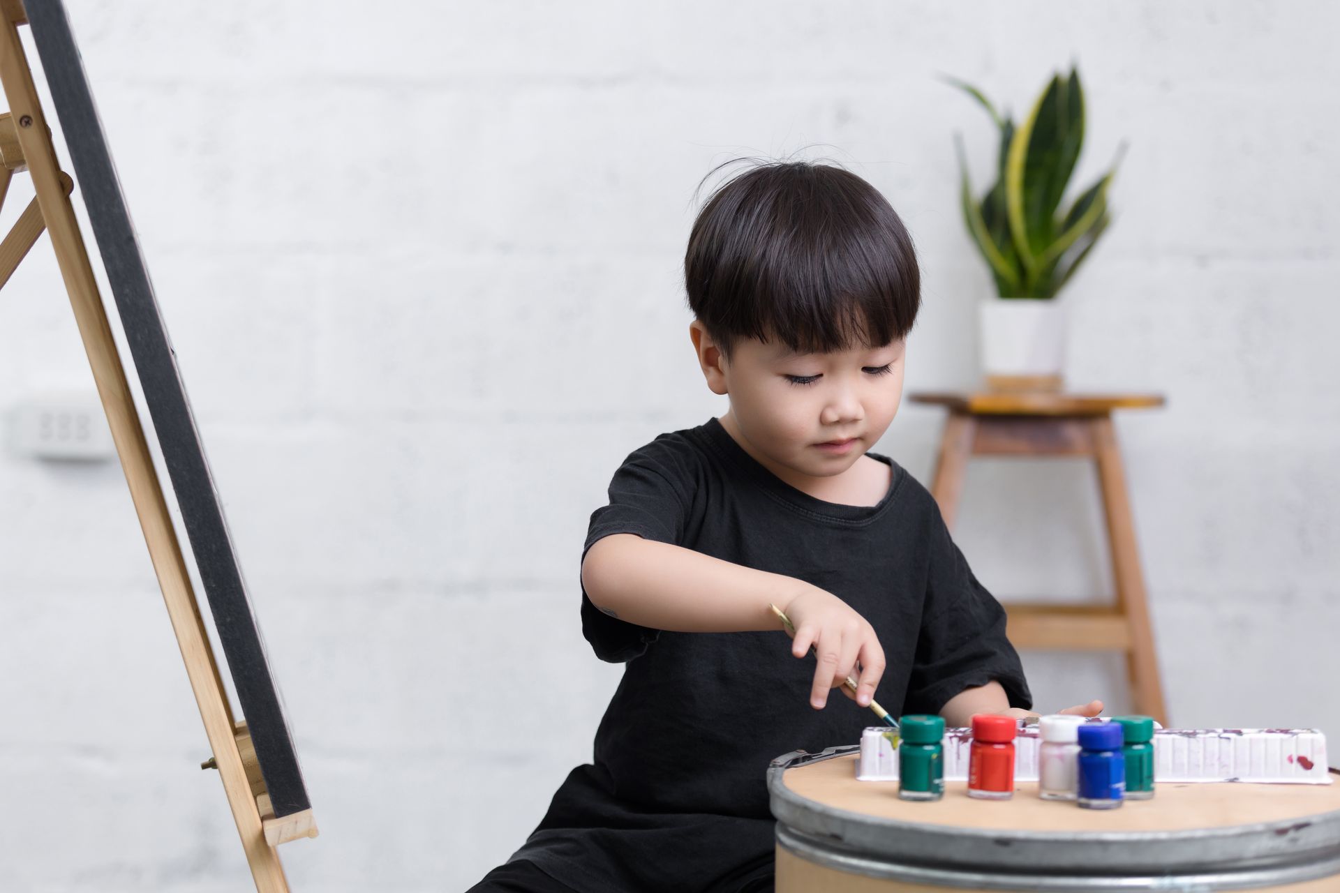 A little boy is sitting on the floor playing with paint.