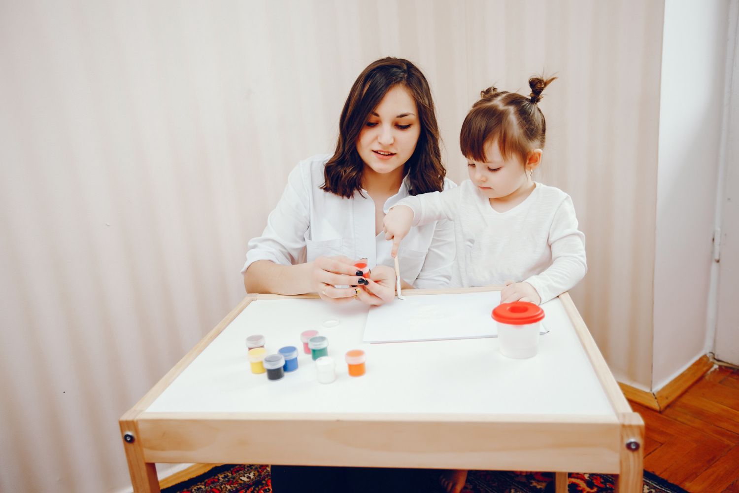 BCBA and a little girl are sitting at a table.