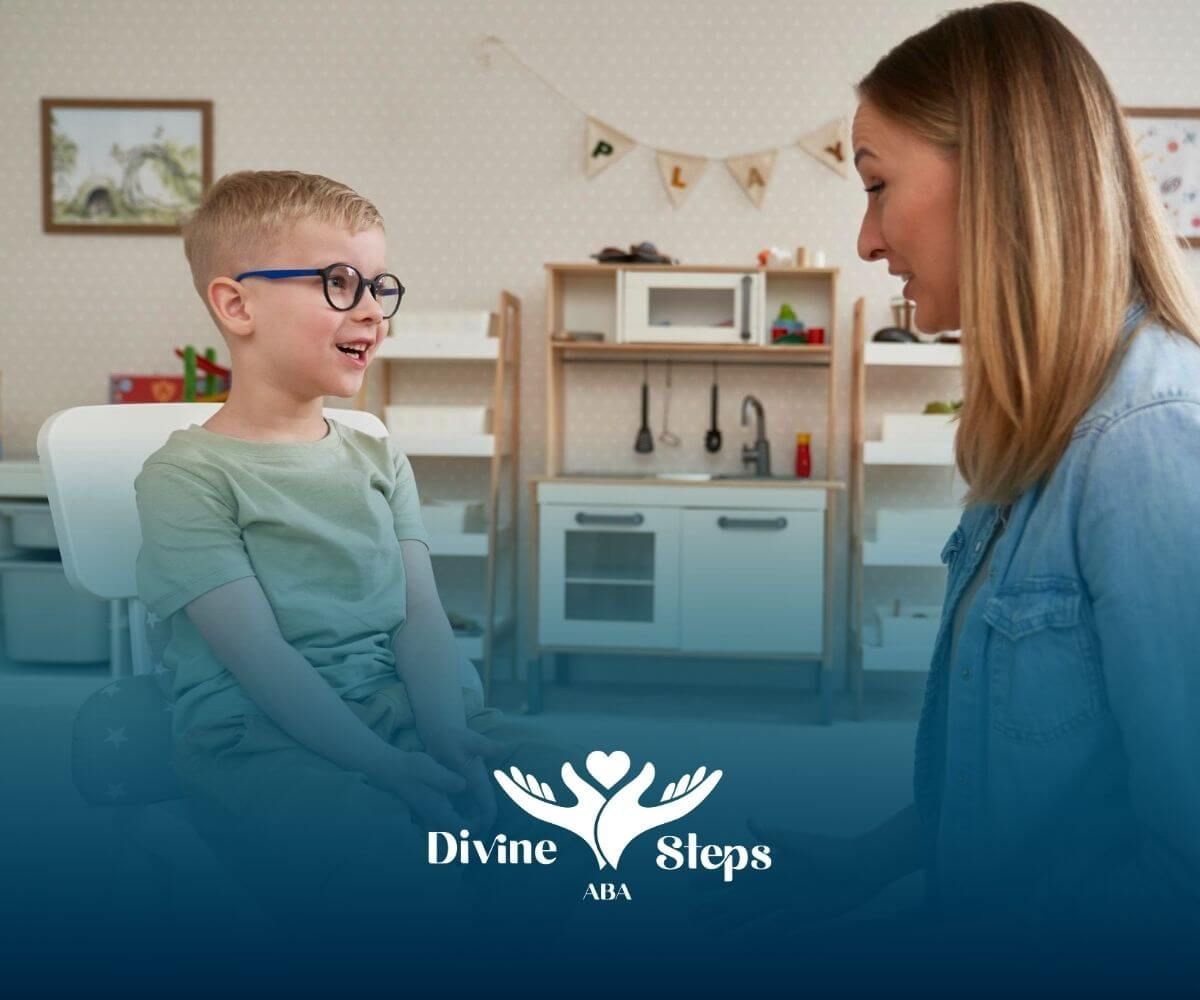 ABA therapist talking with a smiling young boy wearing glasses during ABA therapy.
